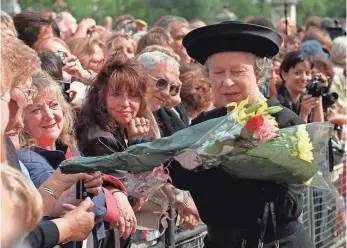  ?? ADRIAN DENNIS, AP ?? Queen Elizabeth II accepts flowers from a well-wisher after arriving at Buckingham Palace Sept. 5, 1997. She gave a televised address that night, and Diana’s funeral was the following day.