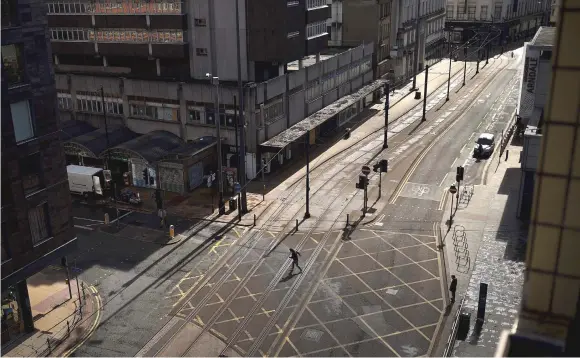  ?? — AFP photo ?? A pedestrian walks across an empty street in Manchester on April 2, as life in Britain continues during the nationwide lockdown to combat the novel coronaviru­s pandemic.