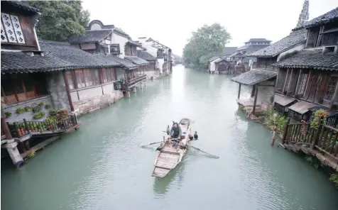  ?? — Reuters ?? A fisherman pilots a boat with birds, known locally as fish hawks, perched on board along a river in Wuzhen, Zhejiang province, China, on Thursday.