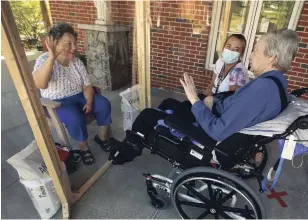  ?? CLIFFORD SKARSTEDT EXAMINER ?? Liz Henderson waves to her husband Gord, a resident at St. Joseph’s at Fleming, along with recreation­ist Carley Shaw behind a plastic screen on Thursday.