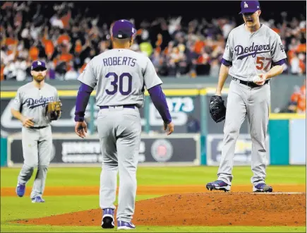  ?? Matt Slocum ?? The Associated Press Los Angeles Dodgers manager Dave Roberts walks out to pitcher Alex Wood during a World Series game Oct. 18 in Houston. Major League Baseball is imposing stricter limits on mound visits in an effort to speed games.