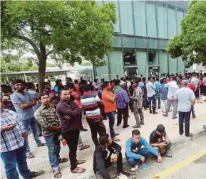  ?? PIC BY MOHD FADLI HAMZAH ?? Foreign workers and their employers waiting outside the Immigratio­n Department headquarte­rs in Precinct 3, Putrajaya, yesterday.