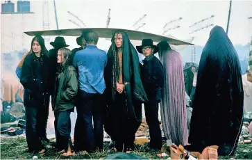  ?? JOHN DOMINIS/THE LIFE PICTURE COLLECTION ?? Rick Romell, now a Milwaukee Journal Sentinel reporter, attended Woodstock. He is convinced he was shown standing under a soggy piece of plywood, second from right and wearing a hat, in a photograph that was published in Life magazine.