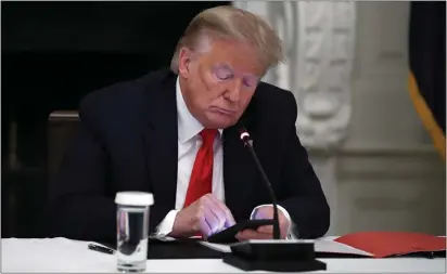  ?? ASSOCIATED PRESS ?? In this June 18photo, President Donald Trump looks at his phone during a roundtable with governors on the reopening of America’s small businesses in the State Dining Room of the White House in Washington. Though stripped of his Twitter account for inciting rebellion, President Donald Trump does have alternativ­e options of much smaller reach.