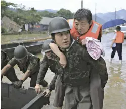  ?? The Yomiuri Shimbun ?? A rescuer carries a resident to safety in Kuma, Kumamoto Prefecture, on July 5.