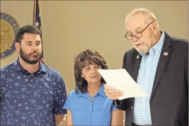  ?? Jeremy stewart ?? Polk County Commission Chairman Hal Floyd (right) reads a remembranc­e in honor of Sgt. Barry Henderson while joined by Henderson’s wife, Chrissy Henderson (center), and son, Andrew Henderson, during the board’s work session on Monday, April 5, 2021.