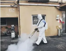  ??  ?? A worker sprays disinfecta­nt in Qingdao. (Chinatopix via AP)