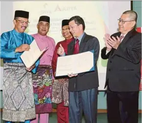  ?? PIC BY FARIZ ISWADI ISMAIL ?? Syarikat Perumahan Negara Bhd (SPNB) chief executive officer Datuk Ahmad Azizi Ali (left) exchanging documents with Ajiya Bhd managing director Datuk Chan Wah Kiang (second from right) in Kuala Lumpur yesterday.