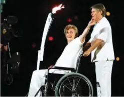  ??  ?? SYDNEY: In this file photo dated Friday, Sept 15, 2000, the 1956 sprint champion Betty Cuthbert who is confined to a wheelchair with Multiple Sclerosis, waves as she is pushed by three-time silver medal winner Raelene Boyle as they carry the Olympic...