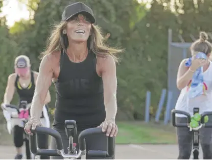  ?? STEVEN SENNE/AP ?? Jeanne Carter (front), co-owner of Fuel Training Studio in Newburypor­t, Massachuse­tts, works out on a stationary exercise bike during a spinning class in a parking lot outside the gym last month.