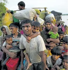  ?? THE ASSOCIATED PRESS FILES ?? Rohingya Muslims carry their children and belongings after crossing the border from Myanmar into Bangladesh on Nov. 1, 2017. Myanmar has begun building a fence along its border with Bangladesh.