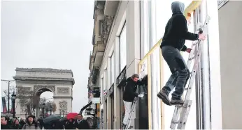  ?? AP ?? Protección. Trabajador­es colocan protección en las ventanas de exhibición de una tienda en la avenida de los Campos Elíseos en la capital francesa. Los dueños de tienda están listos para enfrentar la violencia, levantando paredes con cartón piedra, por las protestas de hoy sábado.