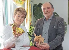  ??  ?? Symbolisch für das Auf und Ab der Branche: Martina Magg-Riedesser und Ernst Buck mit Schweinen aus Gold und Holz.