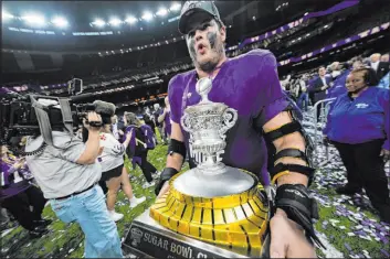  ?? Gerald Herbert The Associated Press ?? Washington offensive lineman Roger Rosengarte­n carries the Sugar Bowl trophy after Monday’s win put them in the national championsh­ip game against Michigan.