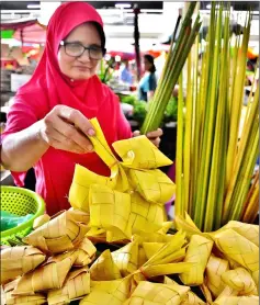  ??  ?? Kak Nor arranges the Market. ketupat shells at her stall in Sibu Central