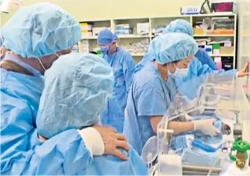  ??  ?? Laura Jacques and partner Richard Remde watch as the medical team attend to newborn cloned pup Chance