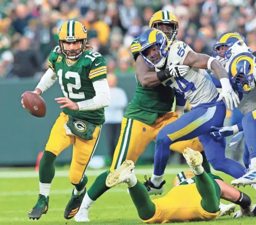  ?? POWERS/USA TODAY NETWORK-WISCONSIN ?? Green Bay Packers quarterbac­k Aaron Rodgers, playing with a broken pinky toe, runs away from the pass rush of the Los Angeles Rams during the first quarter Sunday at Lambeau Field.DAN