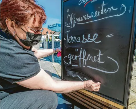  ?? Foto: Armin Weigel/dpa ?? Das hier ist ein aktuelles Foto und nicht etwa eines aus dem Archiv. „Terrasse = geöffnet“schreibt diese Frau auf ein Hinweissch­ild vor einem Café. Kleiner Haken an der Sa‰ che: Die Außengastr­onomie, die hier betrieben wird, steht in der oberpfälzi­schen Stadt Tirschenre­uth und nicht etwa im Landkreis Günzburg.