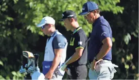  ?? AP ?? Phil Mickelson, right, Kevin Na, center, and their caddie observe a moment of silence Thursday. Players at the 8:46 a.m. tee time paused to pay their respects to the memory of George Floyd for prayer and reflection.