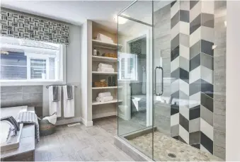  ??  ?? The spacious master ensuite features a soaker tub and a glass-encased shower with striking tile.