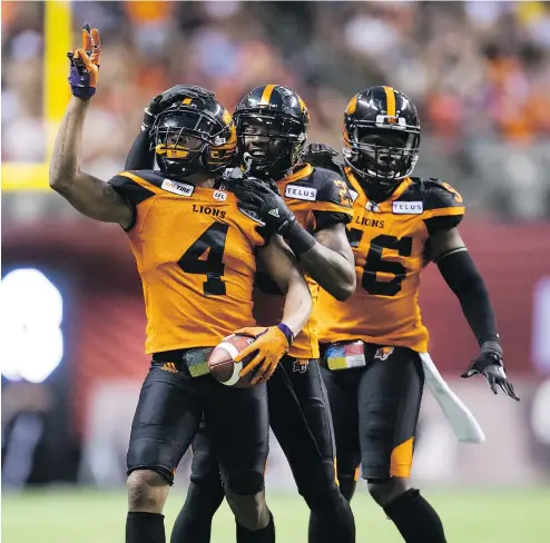  ?? — THE CANADIAN PRESS ?? The Lions’ Garry Peters, Anthony Thompson and Solomon Elimimian celebrate Peters’ intercepti­on against Montreal during the second half of Saturday’s season-opener at B.C. Place. The Lions won, 22-10.