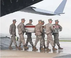  ??  ?? The casket containing the remains of Marine Staff Sgt. Eric Christian, killed in Afghanista­n, arrives at Dover Air Force Base in Delaware on May 7, 2013, where teams of fellow soldiers stand at the ready to do a solemn duty.
