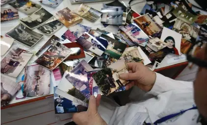  ??  ?? Doctor Yaser Harawi shows photos of himself and his family during an interview with the Associated Press in his office in Belgrade, Serbia. Harawi, who’s lived in Serbia for over 30 years, has found meaning in helping Syrian and other migrants passing...
