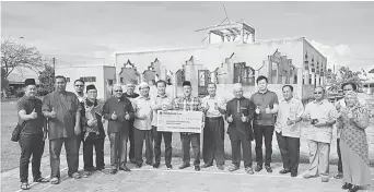  ??  ?? Hii (front, sixth left) presents the cheque to Abang Mohamad, witnessed by members of the surau committee and local community leaders.