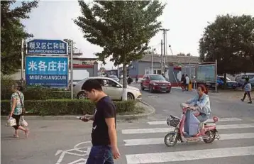  ?? BLOOMBERG PIC ?? People entering the Migezhuang village, which is located across the street from a plant of Hyundai Motors at the outskirts of Beijing. Local entreprene­urs and businesses say demand has dropped sharply in the area.