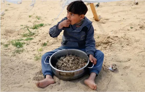  ?? (Ibraheem Abu Mustafa/Reuters) ?? A DISPLACED Palestinia­n child eats at a tent camp amid food shortages in Rafah in the southern Gaza Strip.