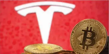  ?? Reuters ?? ↑
Representa­tions of virtual currency Bitcoin are seen in front of the Tesla logo in this illustrati­on picture.