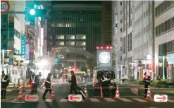  ??  ?? FUKUOKA: Policemen stand guard on a street in Fukuoka yesterday. Police blocked a busy street yesterday as the road, which was hurriedly repaired after collapsing into a giant sinkhole earlier this month, was found to have sunken again. — AFP