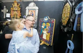  ?? LUIS SÁNCHEZ SATURNO/NEW MEXICAN FILE PHOTO ?? Nicolas Madrid and his daughter, Mila Madrid, 5, check out a winning collaborat­ion piece he did with Best of Show winner Nicolás Otero at the 2017 Traditiona­l Spanish Market.