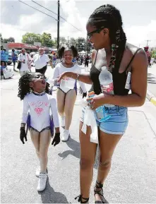 ?? Karen Warren / Houston Chronicle ?? Takaisia Minex shares her water with one of the Pink Diamond Royalettes dancers along the Juneteenth parade route.