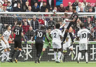  ?? — AP ?? Solid strike: Newcastle’s Jamaal Lascelles (top right) scoring against Swansea during the English Premier League match at the Liberty Stadium yesterday.