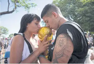  ?? REUTERS ?? Fans kiss a replica World Cup trophy during Argentina’s victory parade in Buenos Aires.