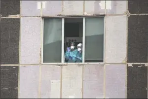  ?? The Associated Press ?? WORKERS: Medical workers gesture from a hospital in Madrid, Spain, on March 18. Experts say Europe has some of the world’s best health systems, but many hospitals have been overwhelme­d with coronaviru­s patients and are ill-equipped to handle the pandemic.