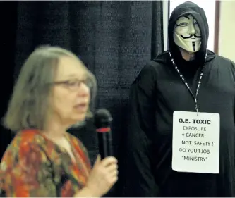  ?? CLIFFORD SKARSTEDT/EXAMINER ?? A protester in a Guy Fawkes mask and grim reaper costume displays a message while attending the GE workers and worker’s compensati­on meetings on Tuesday at the Peterborou­gh Naval Associatio­n hall. See more photograph­s from the meeting in the online...