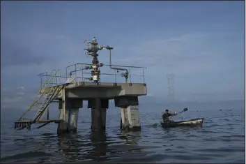  ?? ARIANA CUBILLOS — ASSOCIATED PRESS FILE ?? A fisherman navigates past an inoperativ­e oil drill this month on Lake Maracaibo in Venezuela. A 49-page indictment has charged seven individual­s with conspiring to smuggle oil, purchase sensitive U.S. military technology and launder tens of millions of dollars on behalf of wealthy Russian businessme­n.