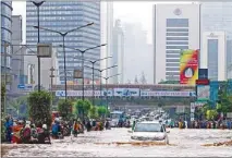  ?? AP ?? Indonesian­s wade through a ßooded main road in Jakarta Thursday.