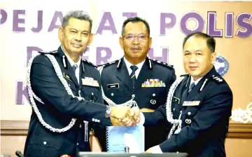  ??  ?? Abang Ahmad (left) officially hands over the duties as Kuching OCPD to Ng, witnessed by Zamani.