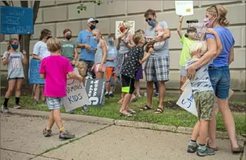  ?? Ben Braun/Post-Gazette ?? Ashley Hezel, right, embraces her son Julian, 5, both of Squirrel Hill, during a protest against a two-week delay for the start of school in front of the Pittsburgh Public Schools Adminstrat­ion Building on Wednesday in Oakland.