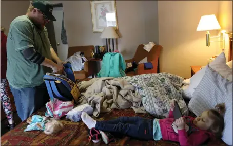  ?? ANDA CHU — STAFF PHOTOGRAPH­ER ?? Camp Fire evacuee Dustin Kimball packs a bag in the room he is sharing with daughter Natalee, 3, and girlfriend Sarah Zigler at the Pacific Motel in Gridley.