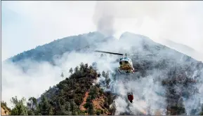  ??  ?? A helicopter gathers water from the Merced River to fight the Ferguson Fire along steep terrain behind the Redbud Lodge near El Portal along Highway 140 in Mariposa County, Calif., on Saturday. ANDREW KUHN /THE MERCED SUN-STAR VIA AP