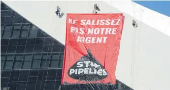  ??  ?? Greenpeace activists hang a banner from Montreal’s Olympic Stadium on Thursday.