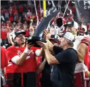  ?? STEVE MARCUS — THE ASSOCIATED PRESS ?? Utah coach Kyle Whittingha­m, right, hands the trophy to QB Cameron Rising, center, after Utah defeated Southern California in the Pac-12 Conference championsh­ip.