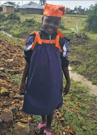  ??  ?? A Kenyan girl wears a dress made from a pillowcase.