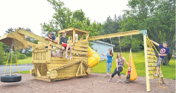  ?? SHARON MONTGOMERY-DUPE/CAPE BRETON POST ?? Albert MacKay, from left, relaxes on a bulldozer playset with his wife Elaine, son Brian, neighbour Noline Francis and her children Kaley, 21, Jolton, 3, and Jaron, 12. MacKay built the playset for Francis to pay her back for showing up with dinner for him every night while Elaine and Brian were in Halifax for Brian’s cancer treatment.