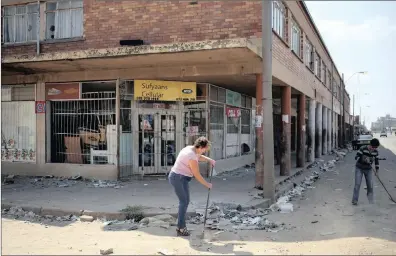  ?? PICTURE: REUTERS ?? Locals clean up after overnight looting, when protesters took to the streets to demonstrat­e against what they see as the killing of a boy in Coligny, North West, in April.