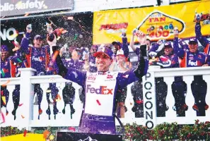  ?? The Associated Press ?? ■ Denny Hamlin celebrates after winning a NASCAR Cup Series race at Pocono Raceway Sunday in Long Pond, Pa. NASCAR stripped Hamlin of his win when his No. 11 Toyota failed inspection and was disqualifi­ed, awarding Chase Elliott the Cup Series victory.